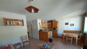 Un ambiente compatto con angolo cottura, zona pranzo e area salotto con divano e poltrone.