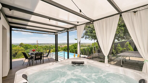 Ein Whirlpool mit Blick auf ein Schwimmbecken und die Landschaft.