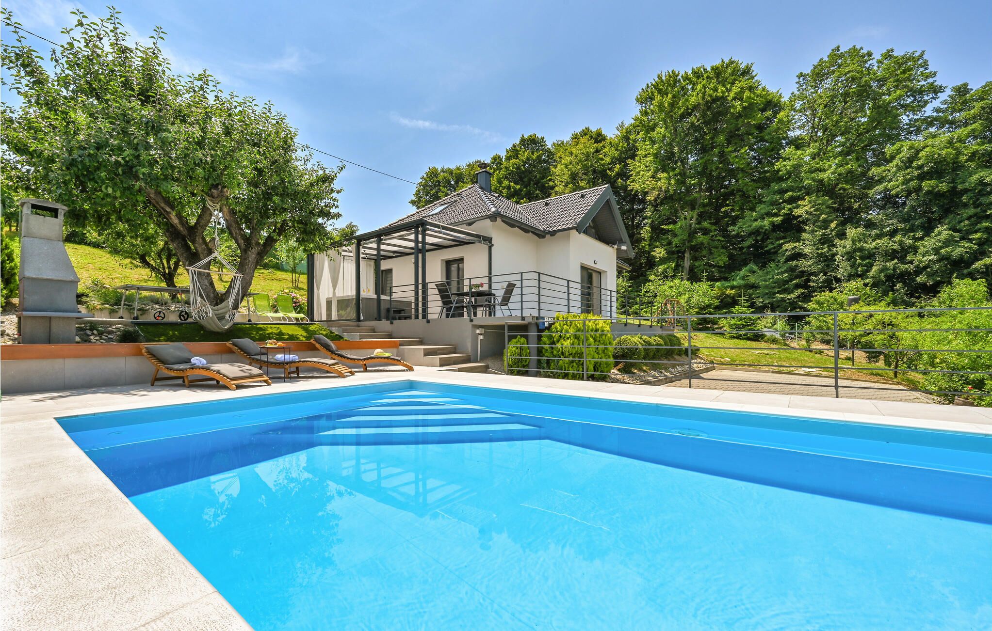 A modern house with a swimming pool, outdoor seating, and a garden.