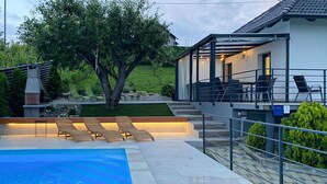 Ein modernes Haus mit Swimmingpool, Außenbereich mit Sitzgelegenheiten und einer überdachten Terrasse.