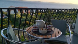 A balcony with a round table, two chairs, a pitcher, mugs, a bowl of cookies, and a pineapple. - Large 95 m2 apt w. the sea View, Balcony and gar (Podstrana)