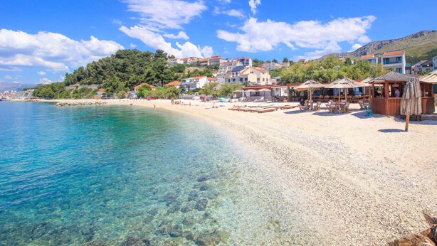 A beach with clear water, a sandy shore, and buildings in the background. - Large 95 m2 apt w. the sea View, Balcony and gar (Podstrana)