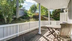 Une terrasse couverte avec une balustrade blanche, une table en bois et une chaise.