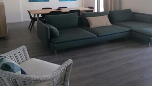 A modern living room with a sectional sofa, a dining table with chairs, and two abstract paintings on the wall.