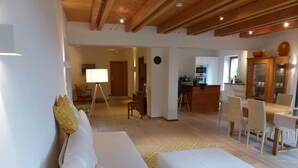 En moderne stue med sofa, spisebord og et køkkenområde.