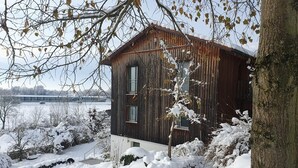 En træhytte med et stort vindue og udsigt til et sneklædt landskab.