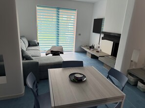 Ein modernes Wohnzimmer mit einer Couch, einem Esstisch und einem Fernseher.