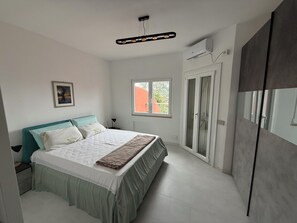 Ein Schlafzimmer mit Bett, Fenster, Klimaanlage und Kleiderschrank.
