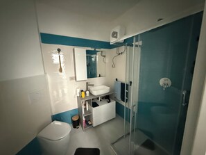 Ein modernes Badezimmer mit Toilette, Waschbecken, Spiegel und Dusche.