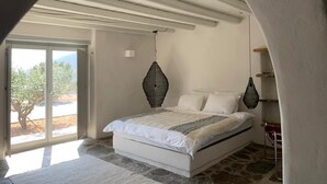 A bedroom with a bed, a large window, and a stone floor. - La Bergerie Dantiparos (Antiparos)