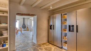 A hallway with stone flooring, a white ceiling, and a built-in stainless steel refrigerator with shelves. - La Bergerie Dantiparos (Antiparos)