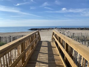 Une promenade en bois qui mène à une plage bordée d’un rivage rocheux.