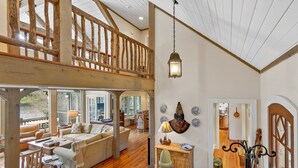 A spacious living area with a high ceiling, wooden beams, and a view of the outdoors. - Beautiful lakefront home nestled into a cove (Lake Toxaway)