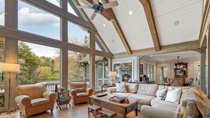 A spacious living area with large windows, a fireplace, and a view of the outdoors. - Beautiful lakefront home nestled into a cove (Lake Toxaway)