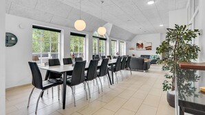 Un comedor moderno con una mesa larga, sillas negras e iluminación colgante.
