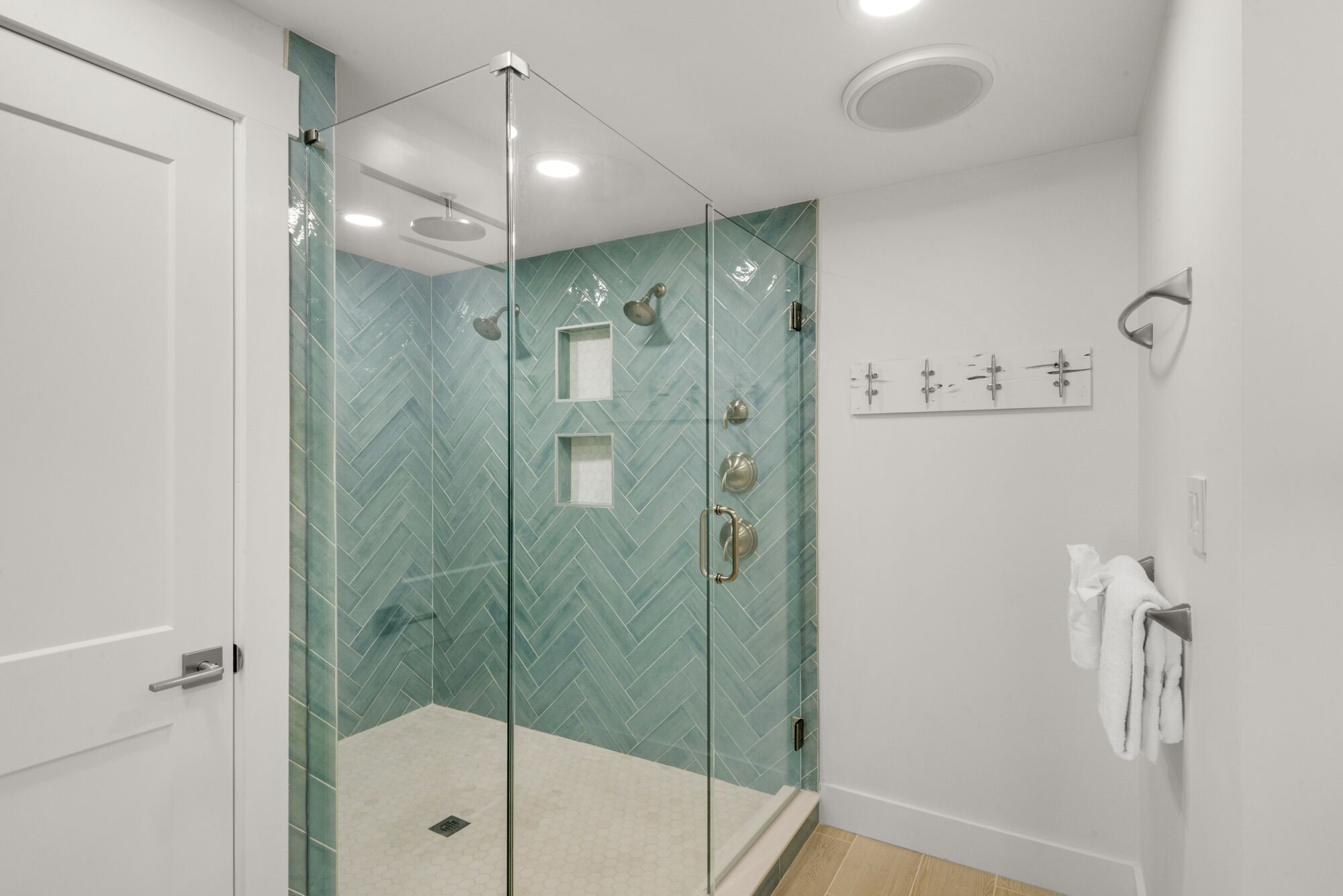 Une salle de bain moderne avec une douche à parois de verre, une porte blanche et un porte-serviettes avec des serviettes.