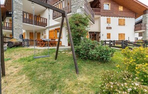 Traditional chalet-style building with a rustic charm, featuring wooden balconies, a stone facade, and a pitched roof.