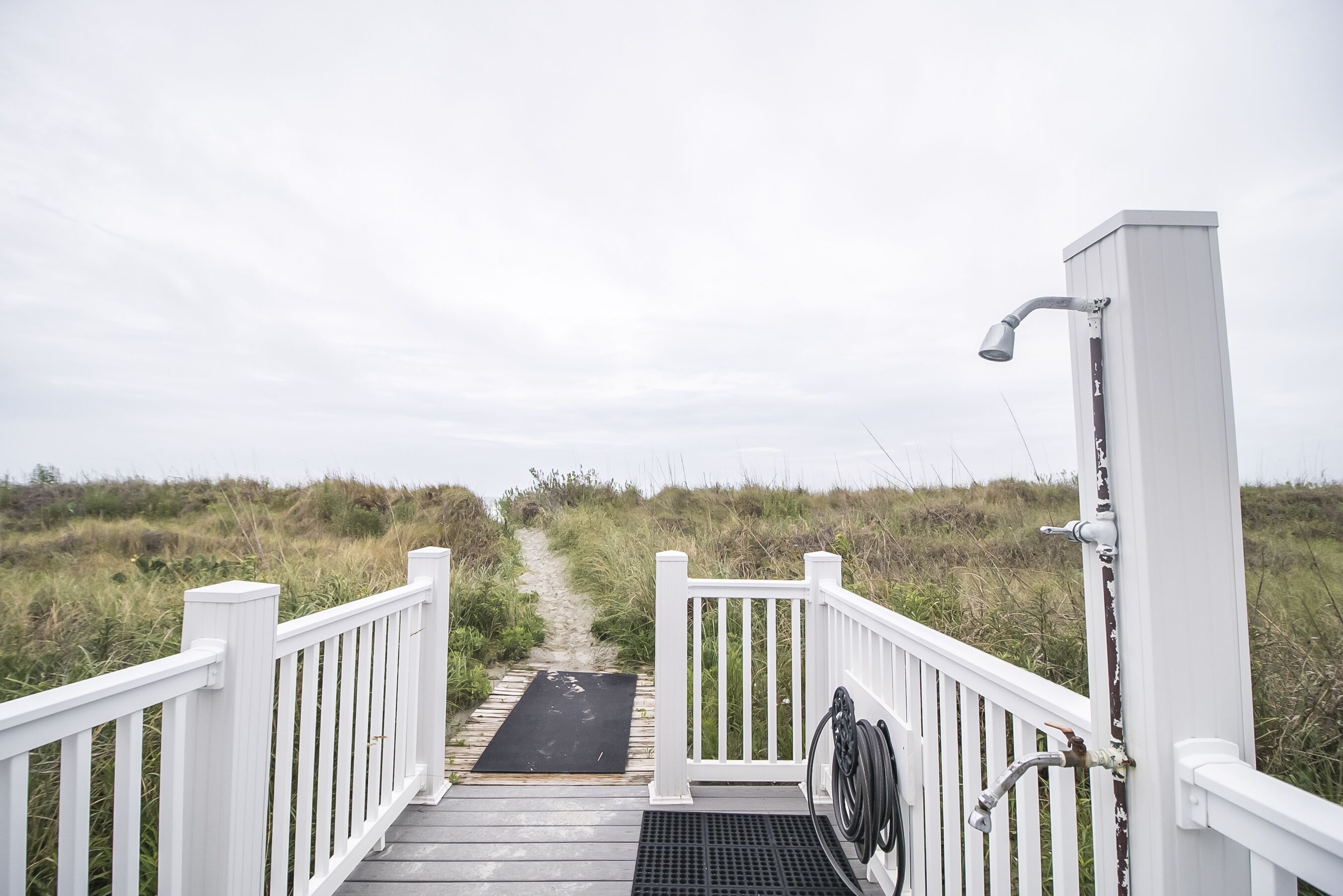 A wooden pathway leading to a white structure with a shower.