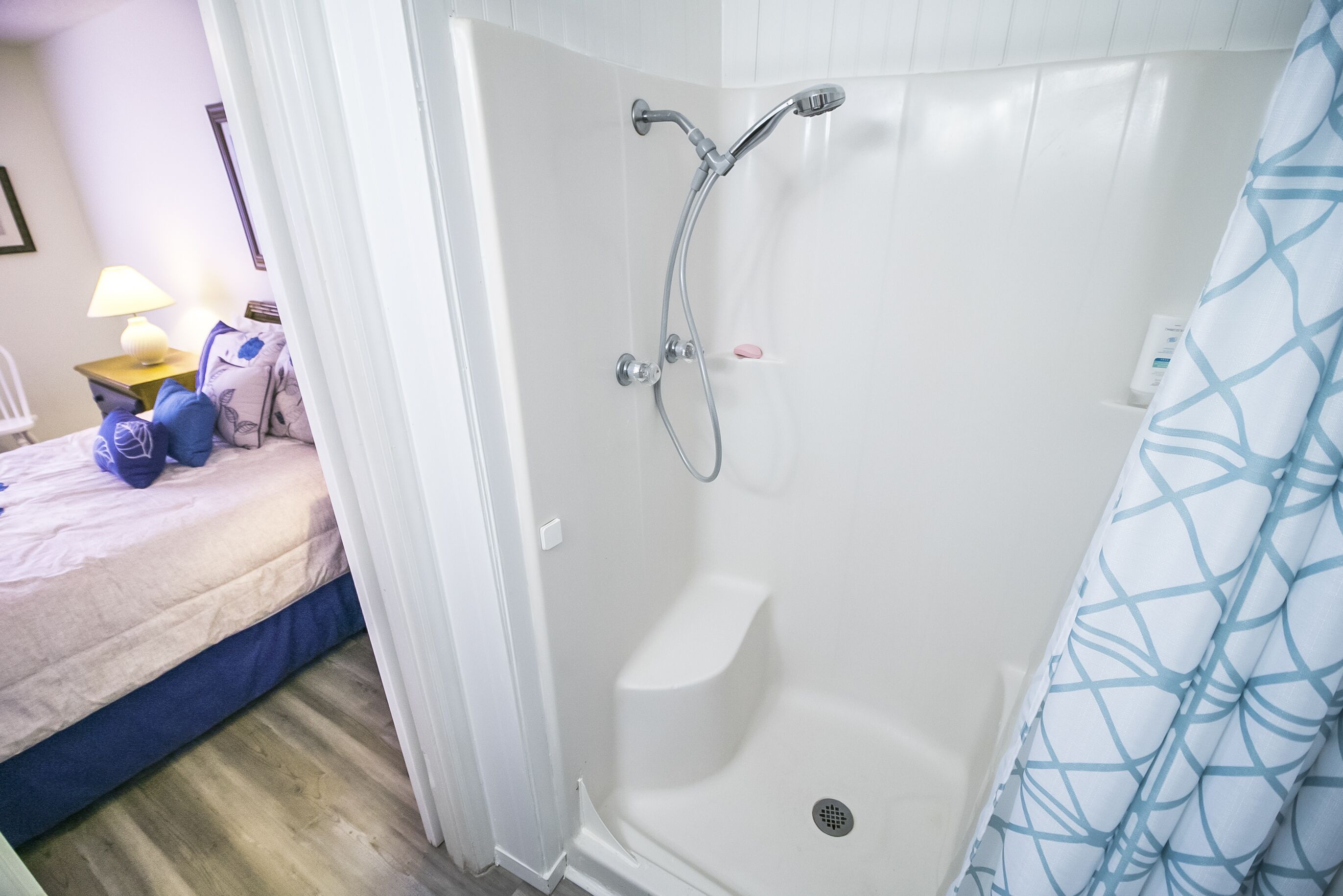 A shower with a handheld showerhead, a built-in seat, and a drain.