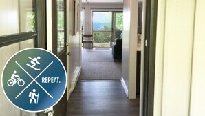 Ein Hotelgang mit Blick ins Freie, ein Schild mit Informationen zu Fahrrad-, Wander- und Rollstuhlgerechtigkeit sowie ein Teppichboden.