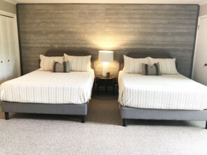A double room with two beds, a wooden headboard, a nightstand with a lamp, and a carpeted floor. - Beech Mountain Retreat With Mountain View<br> (Beech Mountain)