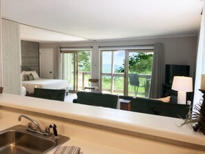 A hotel room with a bed, a desk, a chair, a TV, and a balcony with a view of the outdoors. - Beech Mountain Retreat With Mountain View<br> (Beech Mountain)