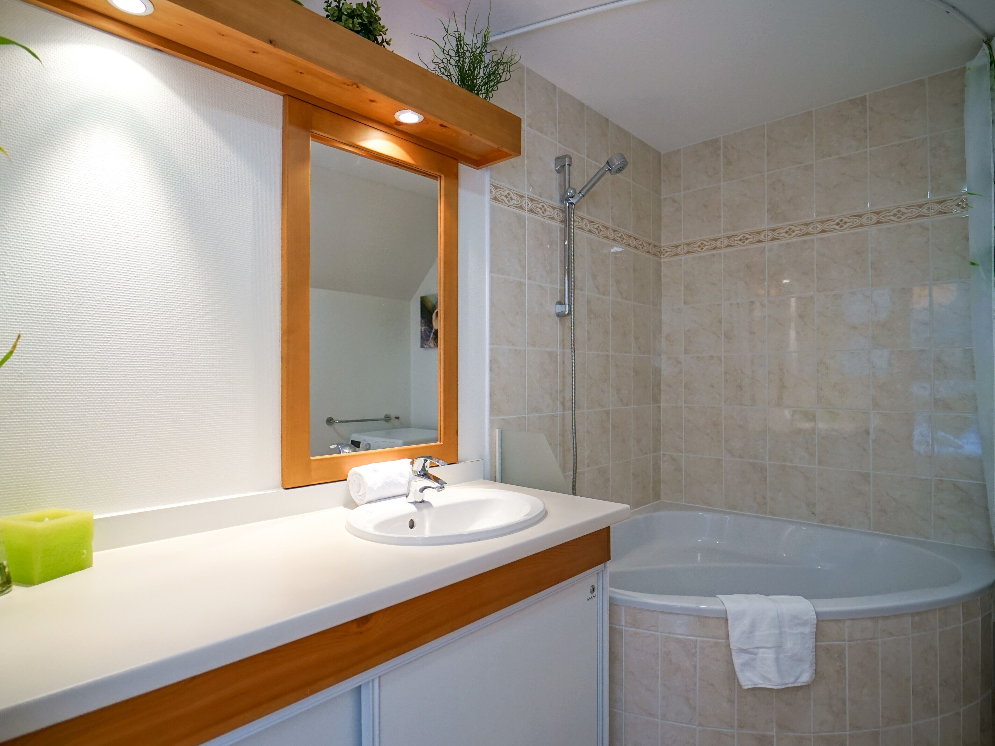 Een badkamer met een wastafel, spiegel en bad.