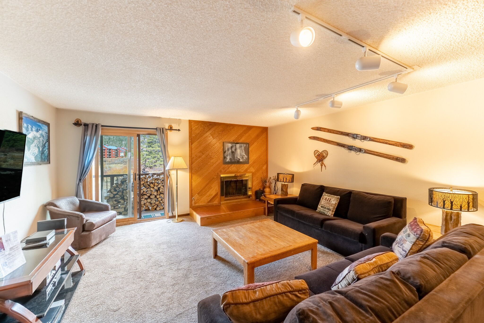 A cozy living room with a fireplace, a sofa, a coffee table, and a TV.