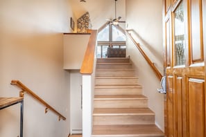 A wooden staircase with a handrail, a window at the top, and a door with a glass panel.