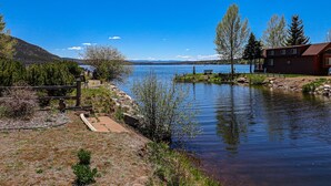 A lakeside cabin with a dock, surrounded by trees and a clear view of the lake. - Edgewater Vista - Waterfront home, sleeps 6, short drive or walk to town! (Grand Lake)