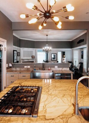 A modern kitchen with a central island, a gas stove, and a chandelier.