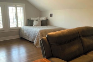 A bedroom with a bed, a leather chair, and a window with blinds. - Monte Vista Home Near Pearl | Pool & Hot Tub (San Antonio)