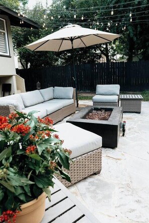 An outdoor patio with a sofa, chair, and fire pit. - Monte Vista Home Near Pearl | Pool & Hot Tub (San Antonio)