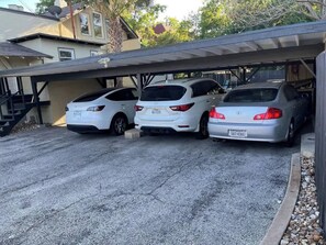 A covered parking area with three white cars parked under a roof. - Monte Vista Home Near Pearl | Pool & Hot Tub (San Antonio)
