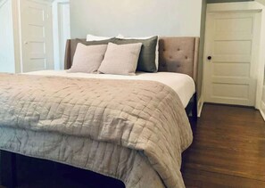 A bedroom with a bed, a headboard, and a door.