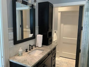 A bathroom with a marble sink, black cabinets, a large mirror, and a towel hanging on the wall.