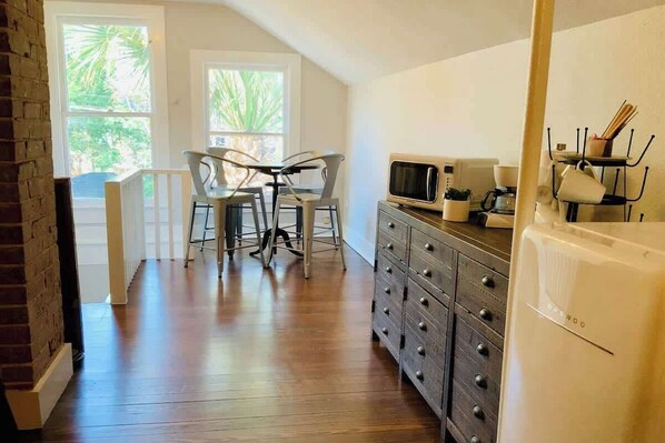 A kitchen with a microwave, stove, and cabinets. There is a dining area with chairs and a table.
