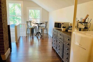 A kitchen with a microwave, stove, and cabinets. There is a dining area with chairs and a table.