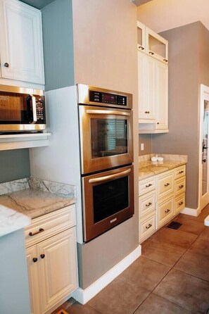 A kitchen with white cabinets, a double oven, and a microwave. - Monte Vista Home Near Pearl | Pool & Hot Tub (San Antonio)