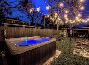 A hot tub with a wooden exterior, surrounded by a wooden fence and a stone pathway. - Monte Vista Home Near Pearl | Pool & Hot Tub (San Antonio)