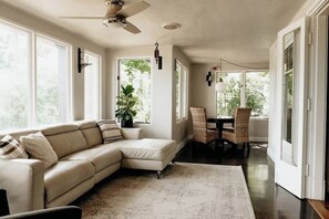 A spacious living room with a large sectional sofa, a dining area with a table and chairs, and a ceiling fan. - Monte Vista Home Near Pearl | Pool & Hot Tub (San Antonio)