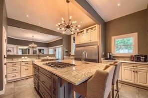 A spacious kitchen with a large island, modern appliances, and a chandelier.