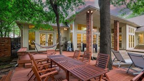 A wooden deck with outdoor furniture, a hammock, and a barbecue area.