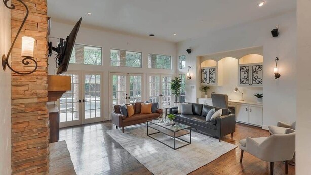 A spacious living room with a stone accent wall, a large window, a fireplace, and a modern fireplace mantel.