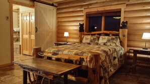 A log cabin bedroom with a wooden bed, a bench, a nightstand, and a window. - Georgetown Lake Escape with Starlink (Anaconda)