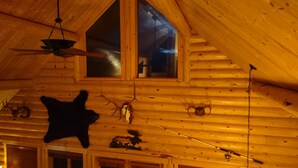 A log cabin interior with a sloped ceiling, wooden walls, and a large window. - Georgetown Lake Escape with Starlink (Anaconda)