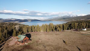 A lodge with a green roof, surrounded by a forest and a lake, with mountains in the background. - Georgetown Lake Escape with Starlink (Anaconda)