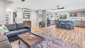 A modern kitchen with a central island, bar stools, and a dining area. - 100-4 Island living at its best!! (Lahaina)