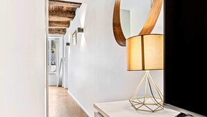 A modern hallway with a wooden ceiling, a large round mirror, a floor lamp, and a flat-screen TV. - Stylish Stay in Grund with City Views (Luxembourg)