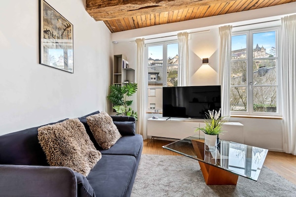 Comfortable living room with plush seating, a large TV, and expansive windows with a view of the neighborhood.